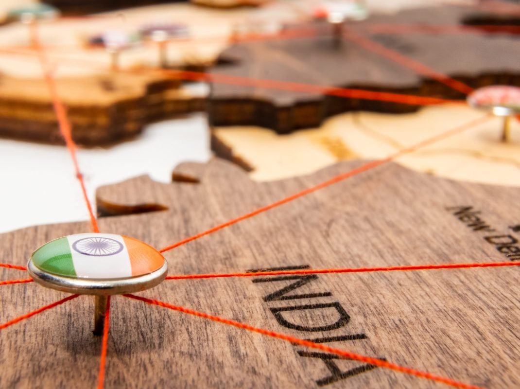 India flag on the pushpin and red thread on the wooden map, close up. Mark of visiting places and planning of vacation and travel routes.