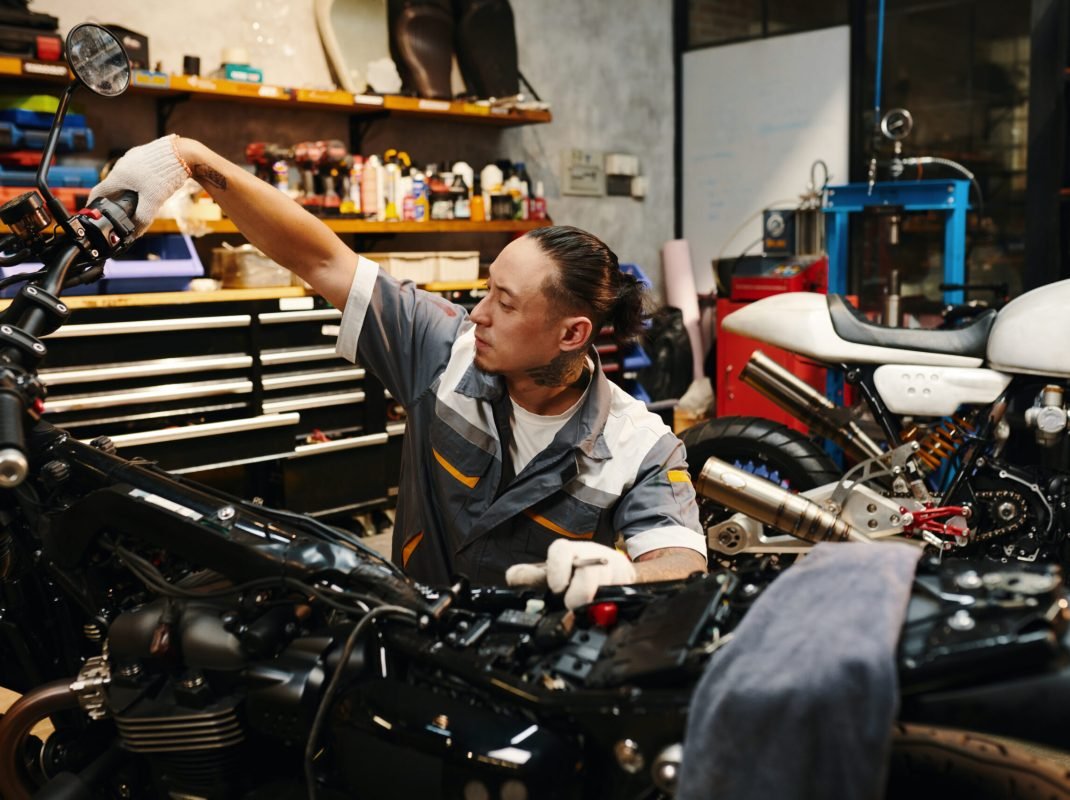Mechanic squeezing and holding clutch lever down to check if engine of motorcycle works